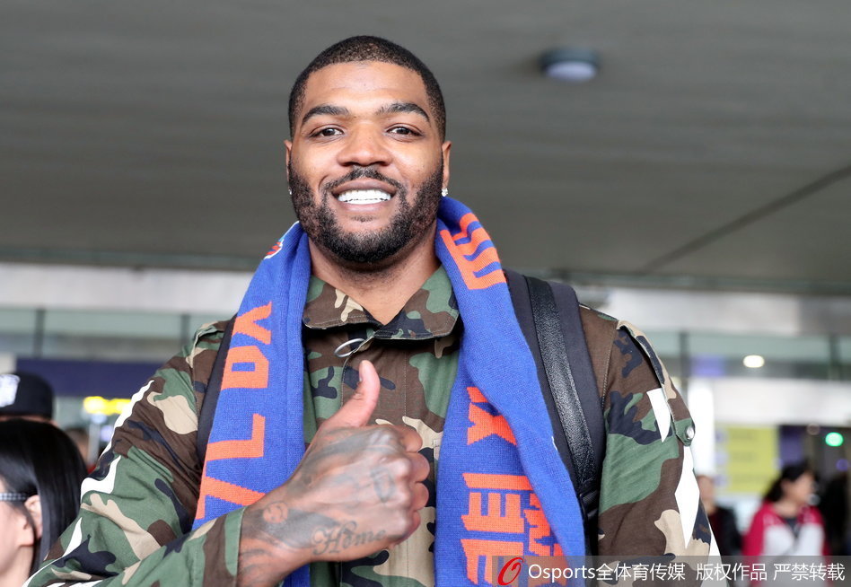 约什·史密斯在酒店大堂遇见队友哈达迪，他像个小兄弟一样跟在哈达迪身后，脸上带着谦逊的笑容，两人正低声交流着什么。