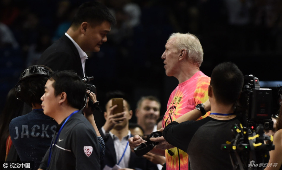 姚明与前中国男篮名宿马健在看台上热切交谈，两人目光如炬，仿佛在共同回顾往昔峥嵘岁月。