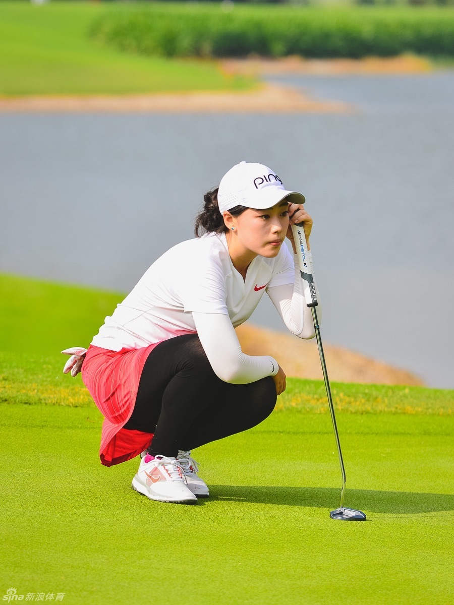 梁恩旗果岭边轻柔切杆，小球划过优美弧线，背景秋叶斑斓如画