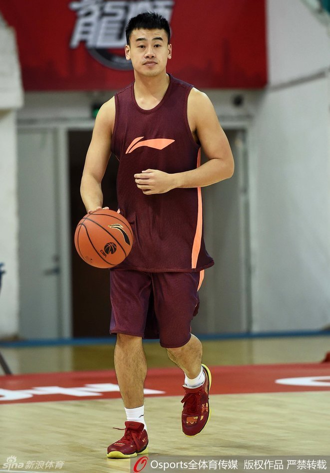 李根和李学林在场边双手紧握，笑容满面地交谈，身后的队友在激烈训练，而这两位老友仿佛回到了并肩夺冠的旧日时光，温情满满。