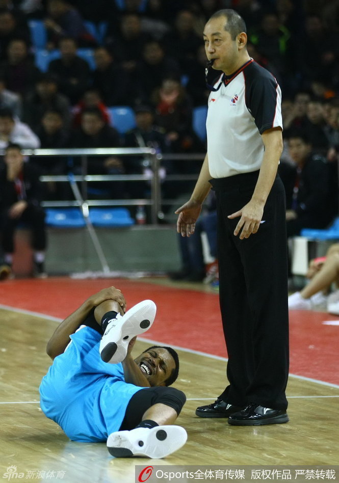 特尔费尔痛苦地倒在地上，双手紧捂受伤的脚踝，面部表情因剧痛而扭曲，身边的队友和对手都焦急地围拢过来，向场边的队医紧急示意。