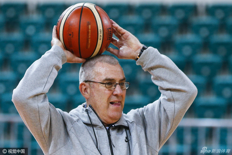 马赫双手持球置于胸前，身体微微弯曲做出对抗姿态，眼神坚定地盯着前方，亲身向队员演示如何在高压防守下稳稳护住球权。