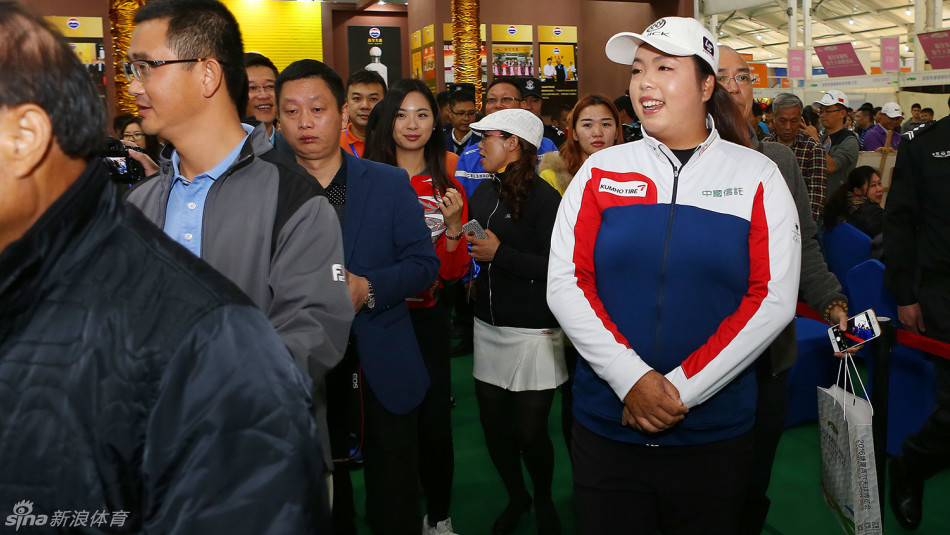 冯珊珊在展馆内饶有兴致地参观，背景是琳琅满目的高尔夫球具与装备展位