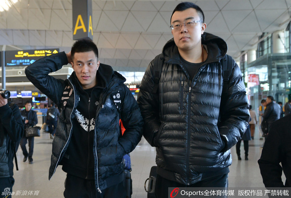 辽宁男篮主教练郭士强指导在机场被热情的球迷团团围住，他面带微笑，正俯身为球迷手中的纪念品签下名字，尽显儒帅风范。