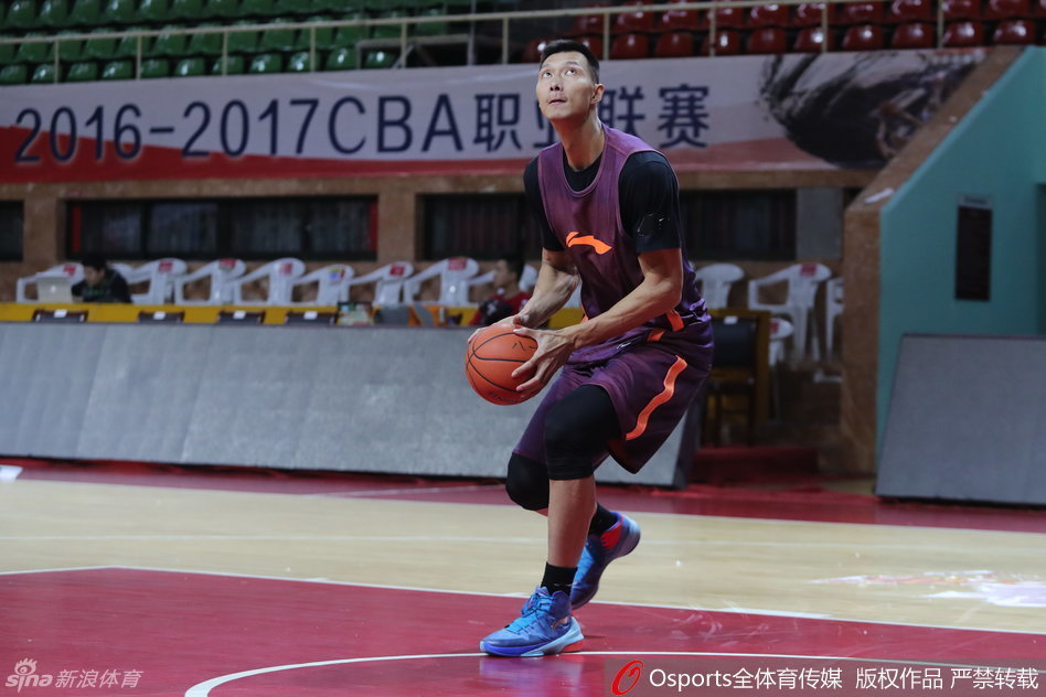 易建联在篮筐侧面进行跳投热身，眼神专注，肌肉线条在训练服下若隐若现。