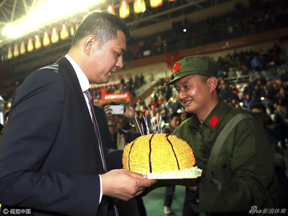 潍坊学院体育馆看台上，青岛球迷高举着巨大的红底白字横幅'巩晓彬生日快乐'，横幅在灯光下格外耀眼，看台上坐满了热情的观众，共同为场下的主教练送上生日祝福。