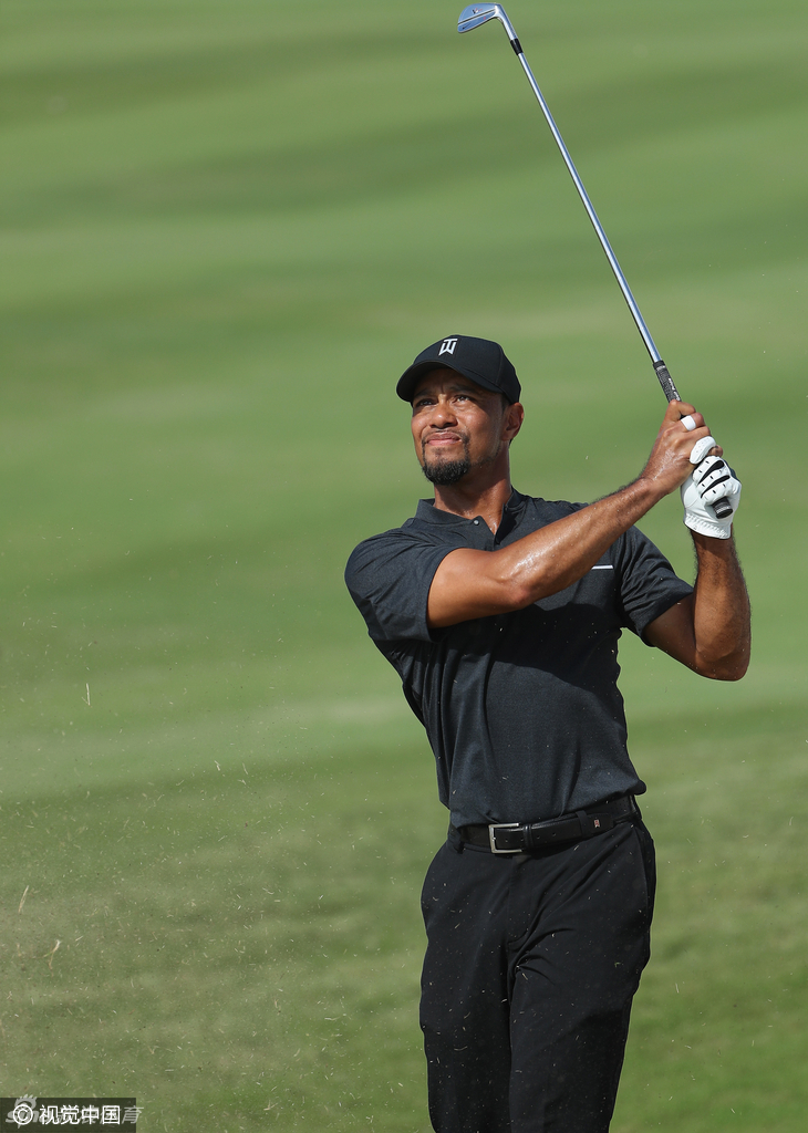 夕阳下的老虎伍兹剪影，他肩扛球包独自离场，背影与长长的影子共同勾勒出王者归来的孤寂与决心。