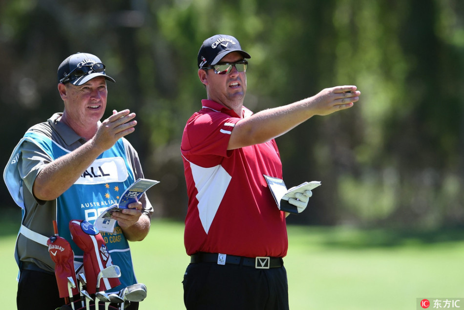 本土黑马球手阿什利·霍尔与他的球童在球道上认真交流,商讨下一杆的策略。