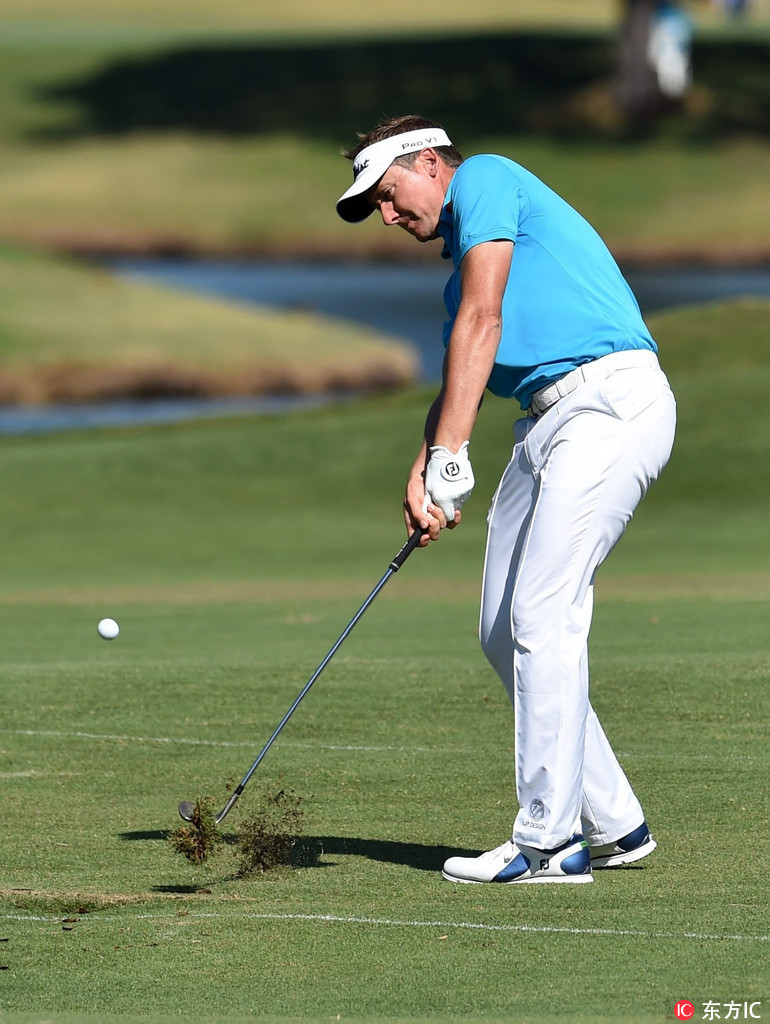 澳大利亚高尔夫名将亚当·斯科特在球道上优雅挥杆,目光坚定地望向前方的果岭。