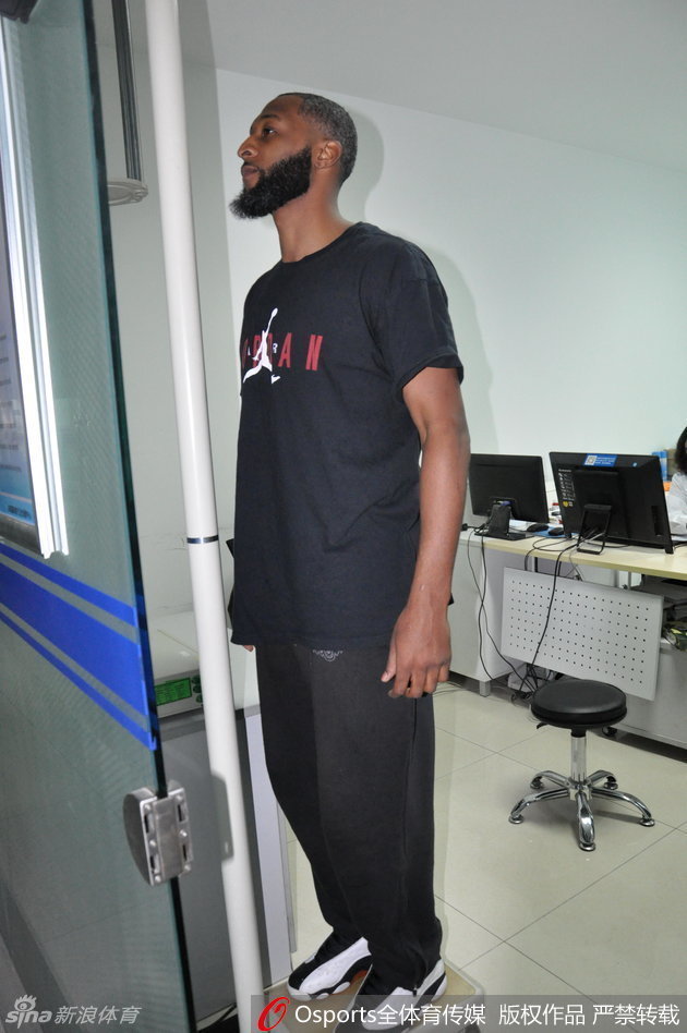 普莱斯正全神贯注地盯着视力表，手指轻轻指向下方，认真的表情如同在比赛中寻找对手防守的破绽。