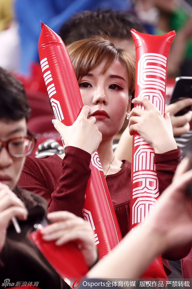 她轻轻举起充气棒抵在脸颊旁，眼神中透露出一丝俏皮与灵动，即便在嘈杂的球场看台上，那份清新脱俗的气质依然让她成为镜头的焦点。