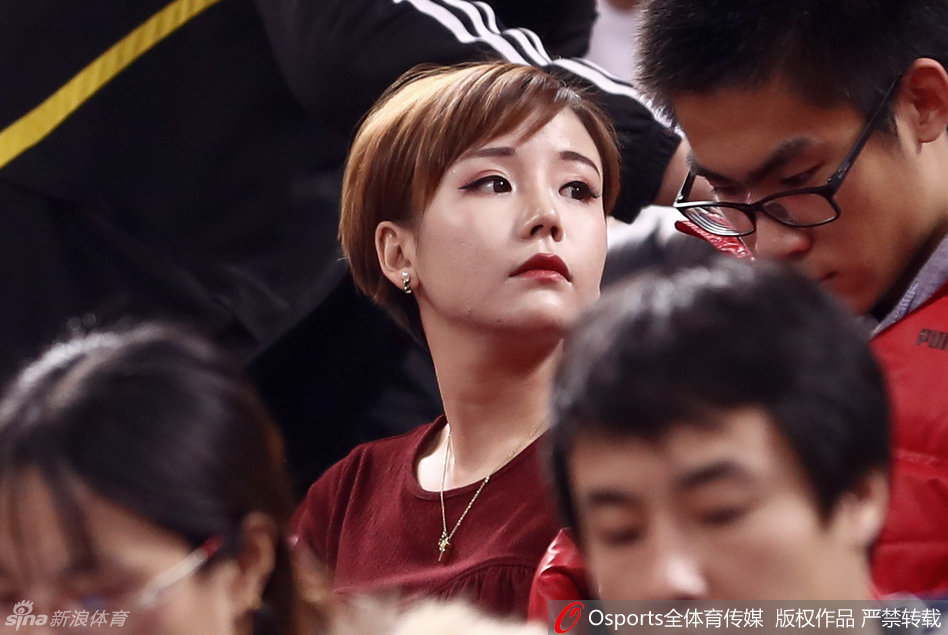 看台上的她拿起手机记录赛场瞬间，脸上浮现出淡淡的笑意，干练的短发与柔美的气质形成独特反差，为激烈的京粤大战增添了一抹温情。