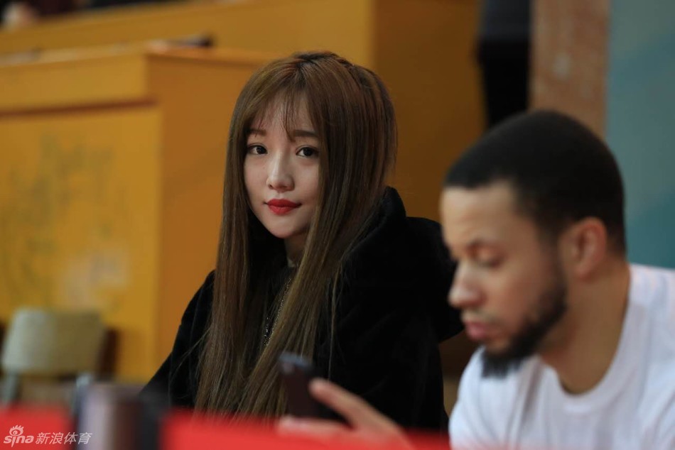 面对镜头，这位八一女球迷展露出温暖而真挚的微笑，她眼神清澈，轻轻抿嘴，手中拿着助威棒，展现出铁杆球迷可爱又亲切的一面。