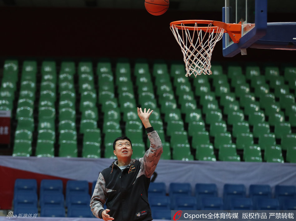 王治郅神情专注地持球准备示范，虽然身着便装，但持球的姿态依旧标准，仿佛瞬间回到了球员时代。