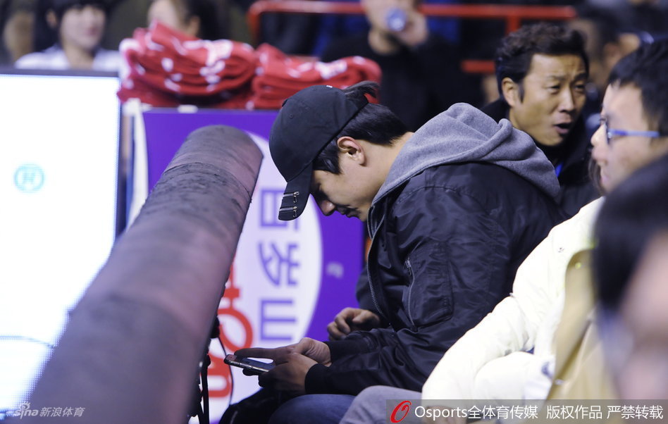 比赛间隙，林更新暂时从激烈的比赛中抽离，低头摆弄手机，似乎是在回复信息或是记录此刻心情，专注的侧脸在球场灯光下轮廓分明。