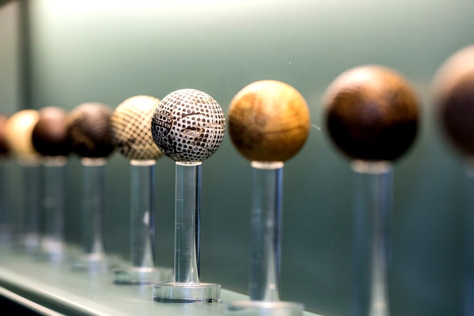 陈列柜中，数支历经岁月的古董高尔夫球杆静卧于丝绒之上，木制杆身纹理清晰，诉说着往昔