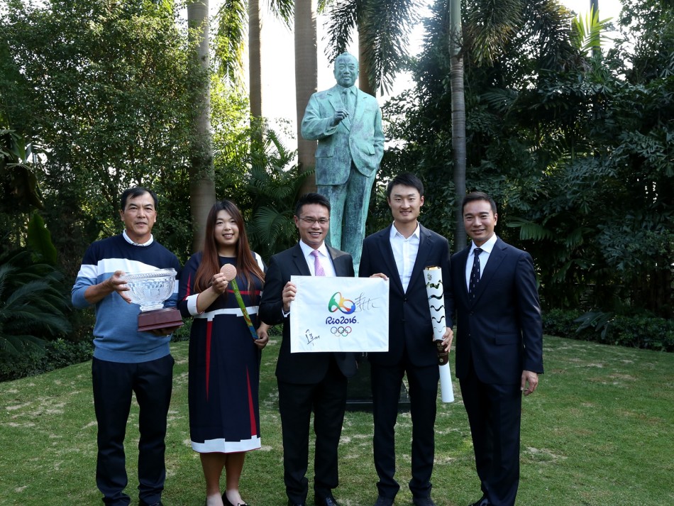 中国高尔夫名将张连伟手持里约奥运会果岭旗，目光坚定，正与身旁青年分享赛场上的激情岁月