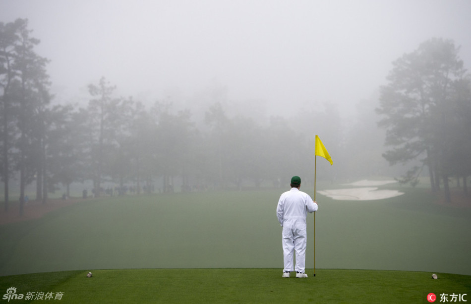 一只戴着白色高尔夫手套的手，正从浓雾弥漫的球道长草中稳稳地捞起一颗小白球，动作充满专注与拯救感。