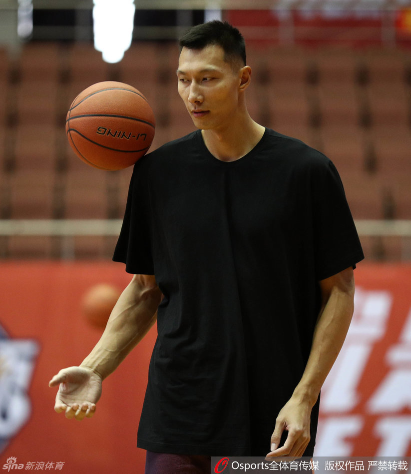 易建联神情专注，在助教的辅助下进行拉伸，身体的柔韧性和力量感展露无遗。