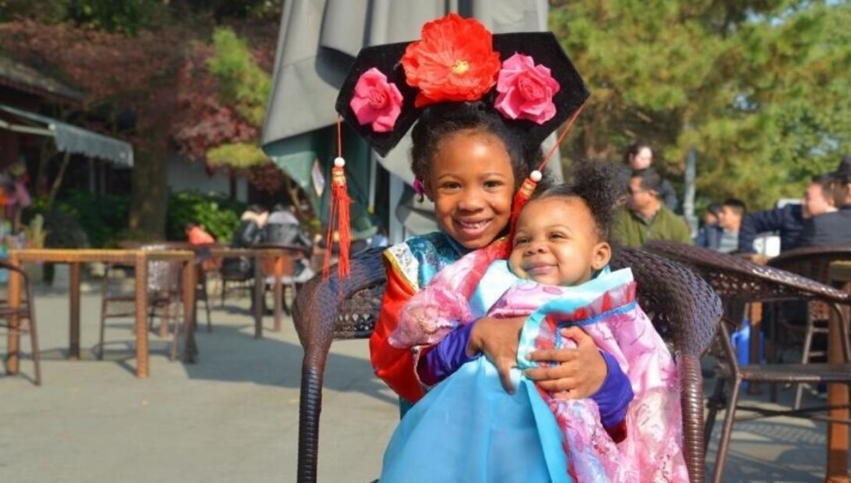 哈德森和未婚妻端坐在中式太师椅上，两个女儿围绕膝前，整张照片透出一种中国传统大家庭的温馨与圆满，极具东方美感