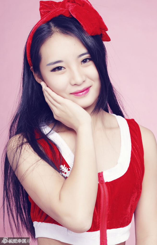 镜头拉近，这位啦啦队员的五官显得尤为精致。她头戴红色圣诞帽，手捧小巧的圣诞树装饰，眼神温柔而明亮，甜美笑容中蕴含着历经风波后的从容与坚定。