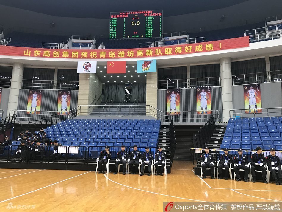 比赛当晚，青岛国信体育馆外围广场上，大批得知比赛取消的球迷神情茫然地聚集在一起，有的低头看着手机确认消息，有的正在与同伴议论，背景是体育馆亮着灯光的外立面。