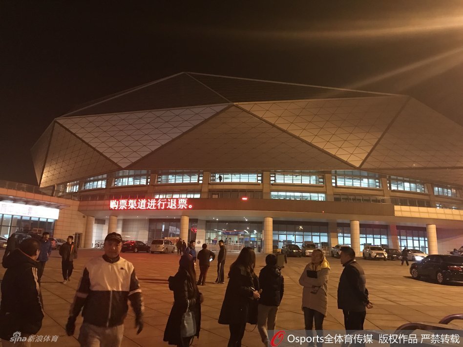 体育馆入口的玻璃门上，贴着一张临时打印的白色A4纸通知，上面清晰地写着关于本场比赛因故改期的告示和退票指引，透过玻璃门能看到馆内仍然灯火通明，却无人入场。