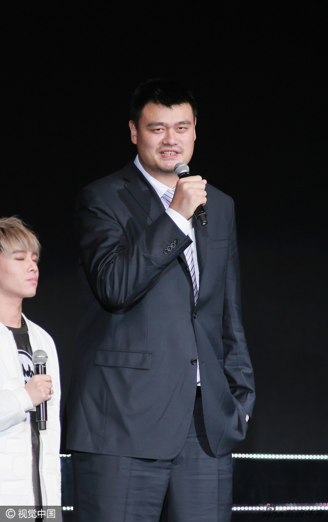 面对热情的香港观众和台上的歌手，姚明露出标志性的憨厚笑容，挥手致意，如同一个温和的巨人在分享新年的喜悦与祝福。