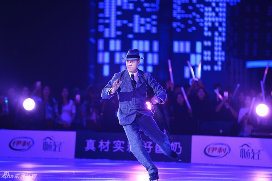 花滑王子普鲁申科在水立方的背景板前留下帅气身影，他身穿深蓝色西装，双手自然垂放，面带标志性的微笑，气质优雅从容。