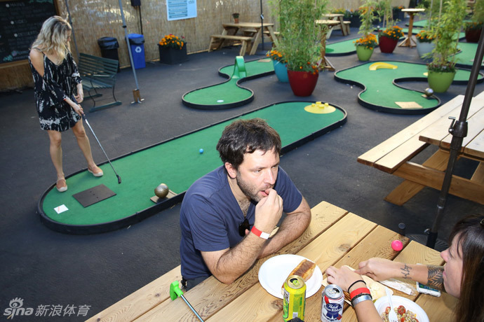 室内迷你高尔夫球场一瞥,荧光色的球道与装饰在紫外灯下发出梦幻的光芒,充满了未来科技感。