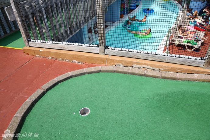 一个设计精巧的复合球道,小球需经过木桥、绕过石景,最终抵达远处的球洞,展现了迷你高尔夫复杂而有趣的地形设计。