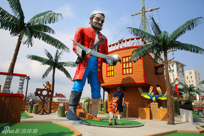 海洋城闹鬼主题迷你高尔夫的一角,骷髅、蜘蛛网与幽暗的灯光营造出神秘又趣怪的氛围,小球正欲穿越一道鬼火萦绕的拱门。