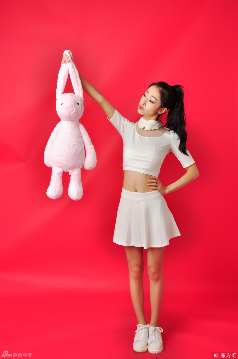 两位队员并肩而坐，白色短裙衬托出修长美腿，一人调皮比耶，一人温柔浅笑，闺蜜般的默契感溢出画面