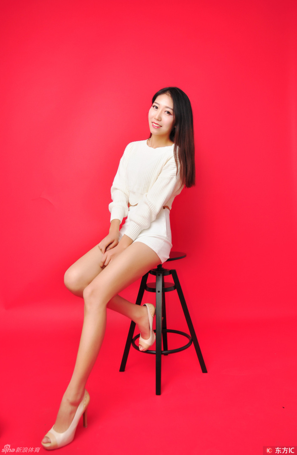 队员单手叉腰站在台阶上，白裙短至大腿，一双美腿笔直修长，眼神自信地望向远方，气场十足