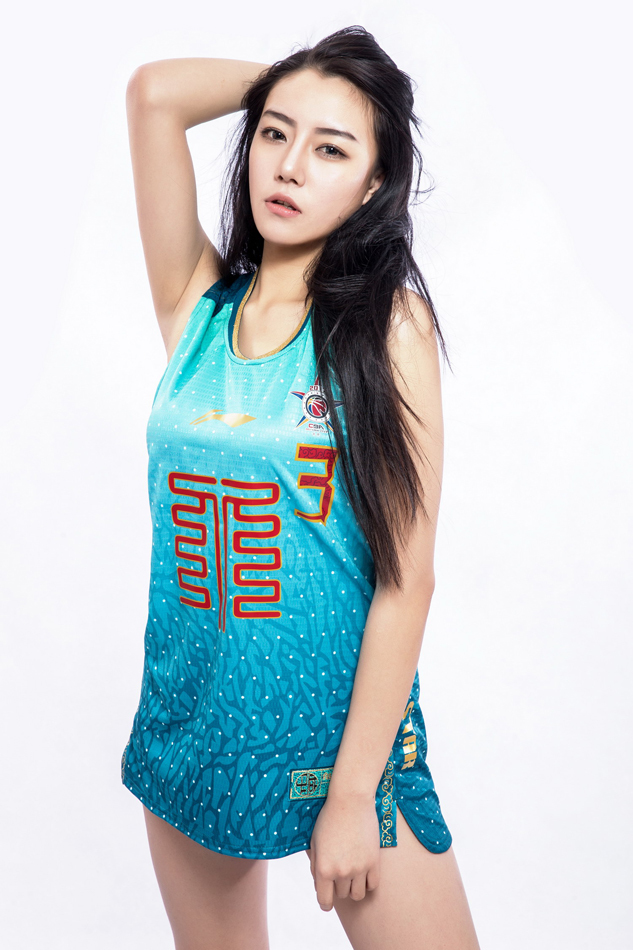 一位气质出众的女神回眸一笑，身后的五棵松体育馆灯光璀璨，她的眼神中充满了对这场篮球盛宴的期待。