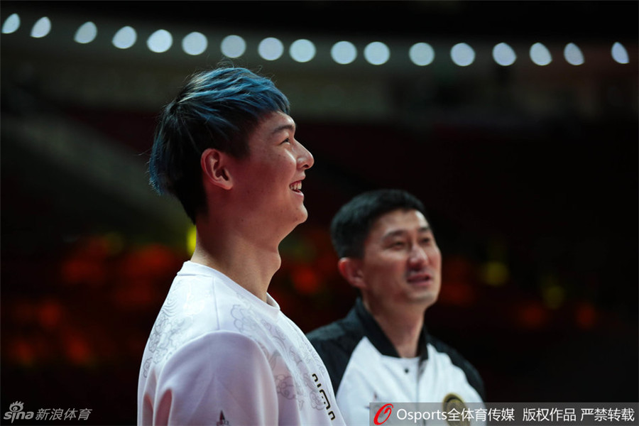 王哲林与杜锋在场边谈笑风生，王哲林笑得眼睛眯成了一条缝，用手捂着脸，杜锋则面带微笑地看着他，气氛轻松愉悦。