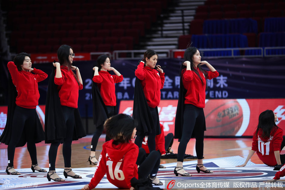 领队正在为队员纠正姿态,女孩伸展手臂线条流畅,形体训练一丝不苟。