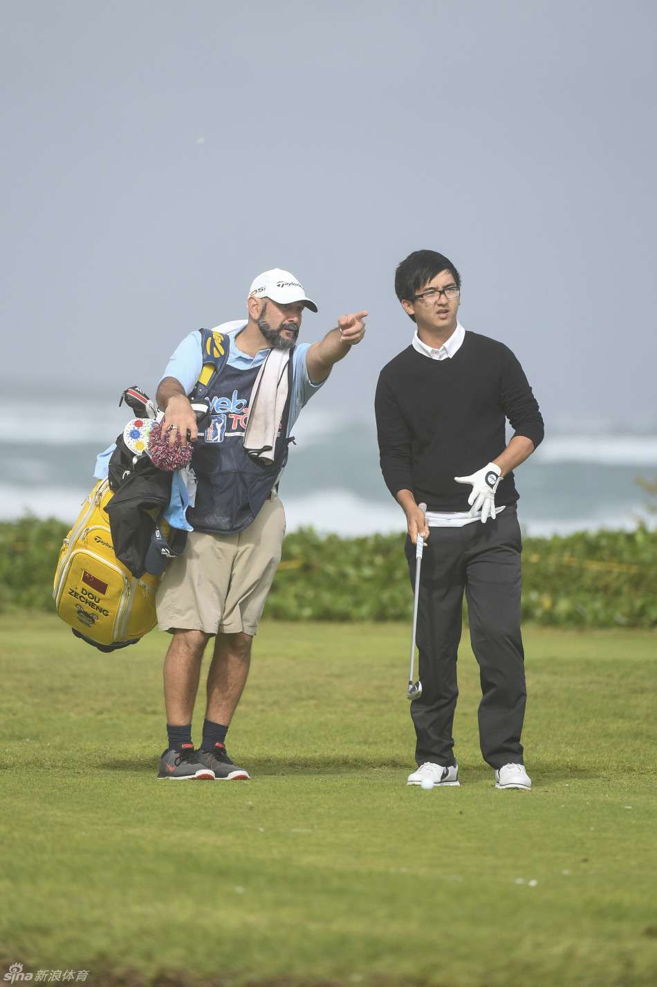 窦泽成在击球前与球童进行战术沟通,两人表情严肃地分析风向与球场策略。