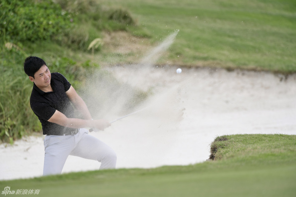 张新军在沙坑中沉着救球，沙坑边缘的细沙被杆头划出一道漂亮的弧线，他专注的神情仿佛世界只剩下眼前的球与旗杆