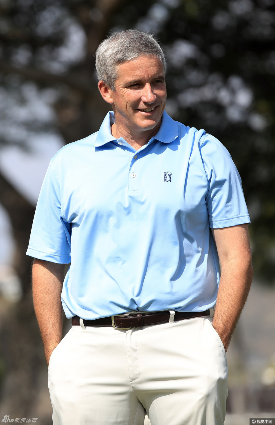 2014年赛事冠军杰米·沃克尔正在果岭上审视推杆线路，他双手扶膝，目光如炬，展现出冠军球员在关键时刻的沉稳与专注。