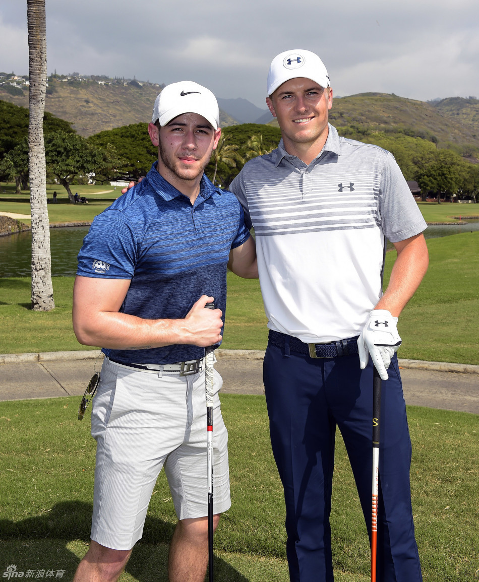 美巡赛新主席杰伊·莫纳汉在赛场边，正与球员凯文·基斯纳亲切交谈，两人面带微笑，气氛轻松。背景是夏威夷典型的蓝天绿树，展现了赛事管理高层与球员之间的紧密联系。