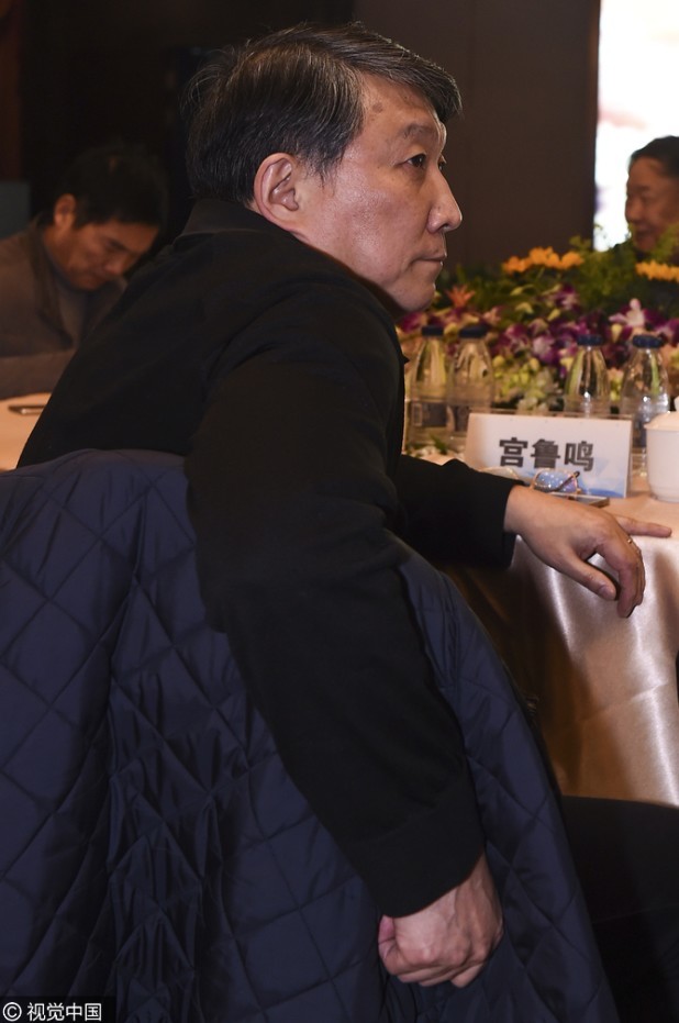 在发布会后台，宫鲁鸣与老朋友苏群相遇，两人双手紧握，面带笑容地交谈，宫指导的眼神中透露出对新工作的期待与坚定。