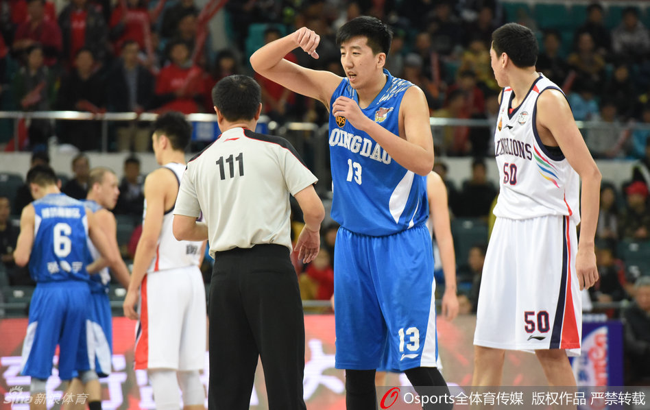 裁判员站在技术台前认真观看录像回放,场边教练组焦急等待,身后是黑压压的观众席