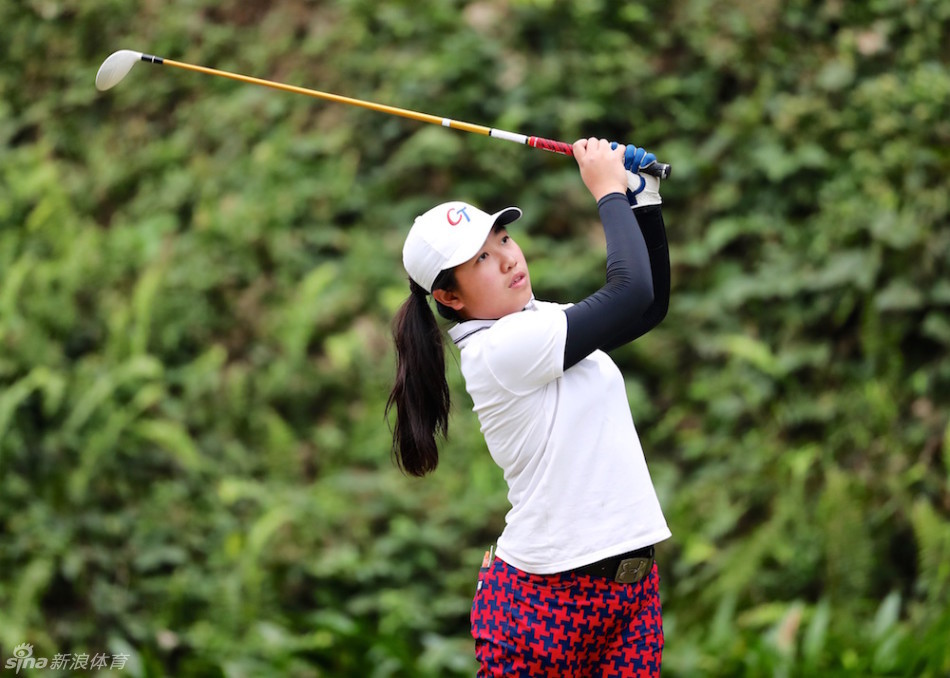年轻的中国高尔夫选手在练习场专注地进行挥杆训练,阳光洒在翠绿的草地上,映照出他们追求梦想的执着身影。
