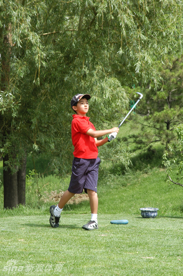 蓝天白云下，小小身影奋力挥动球杆，白色小球划出一道奔向远方的优美弧线。