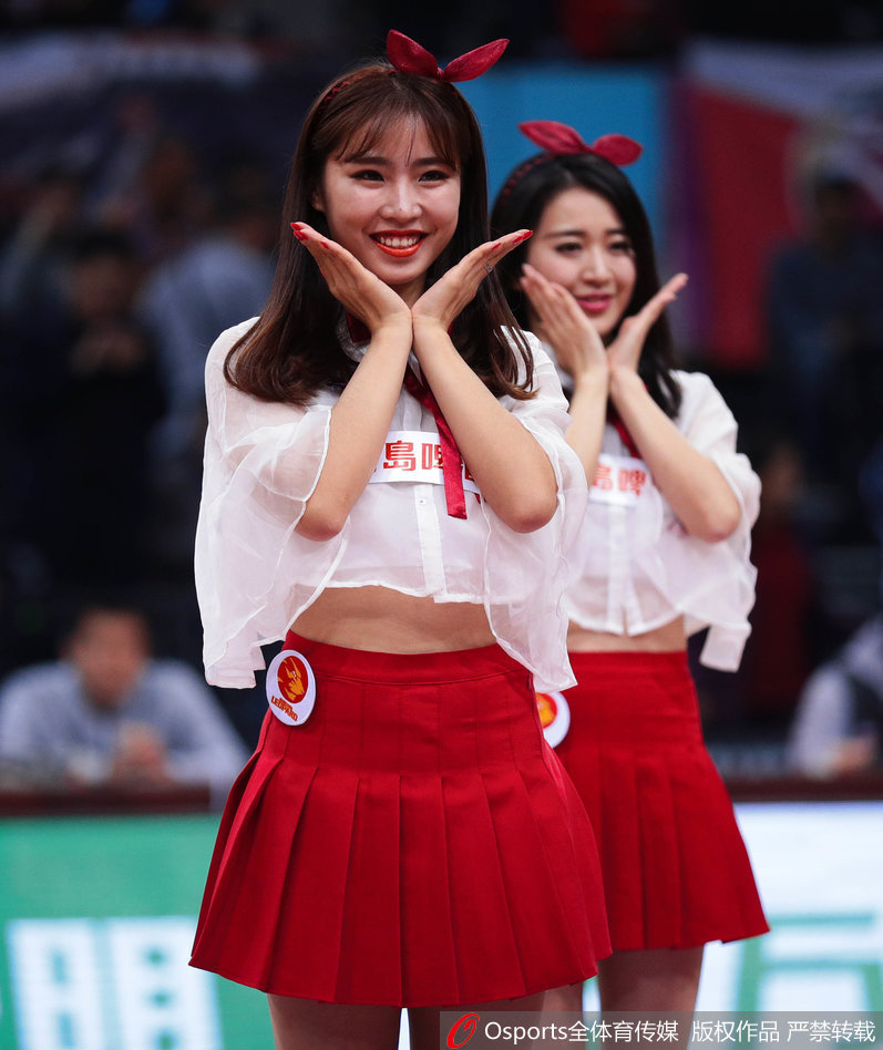 特写镜头下，一位深圳篮球宝贝长发飘逸，烈焰红唇与红色舞裙相得益彰，她眼神专注而充满激情，正在为场上的主队球员加油鼓劲。