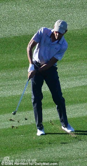 奥巴马站在果岭旁凝神看线，衡量推击路线与力度，身旁球童陪同