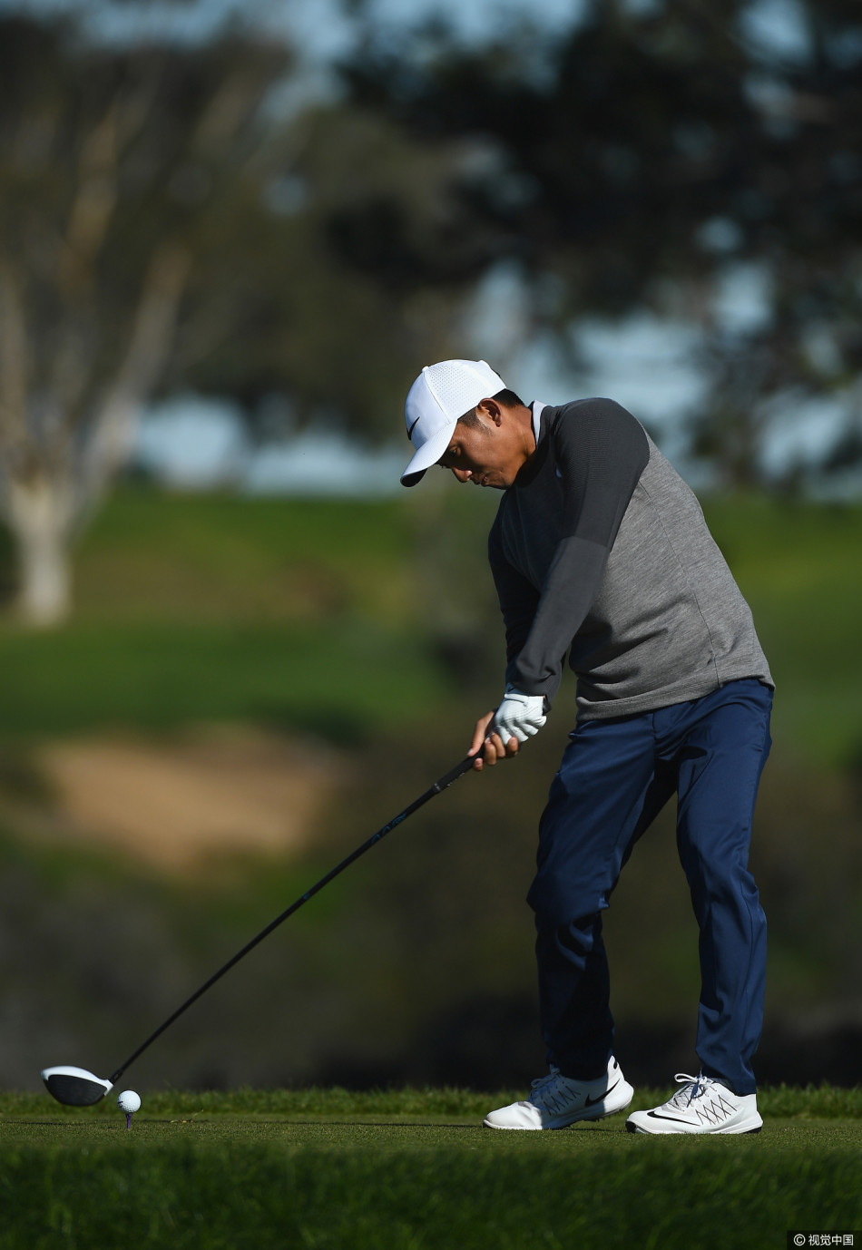 帕特里克-罗杰斯手持其充满赛车科技元素的新款推杆,正在果岭上仔细瞄准,背景是晴朗的比赛日天空。