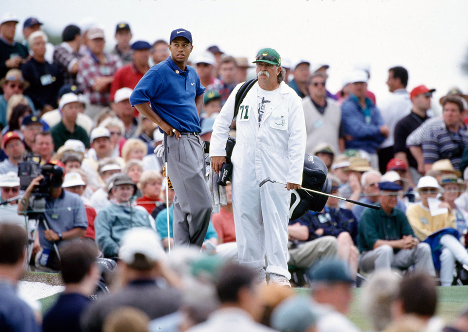 在1999年PGA锦标赛的激烈角逐中，泰格·伍兹于茂密树林间全神贯注地观察球路，准备击出一记关键的救球