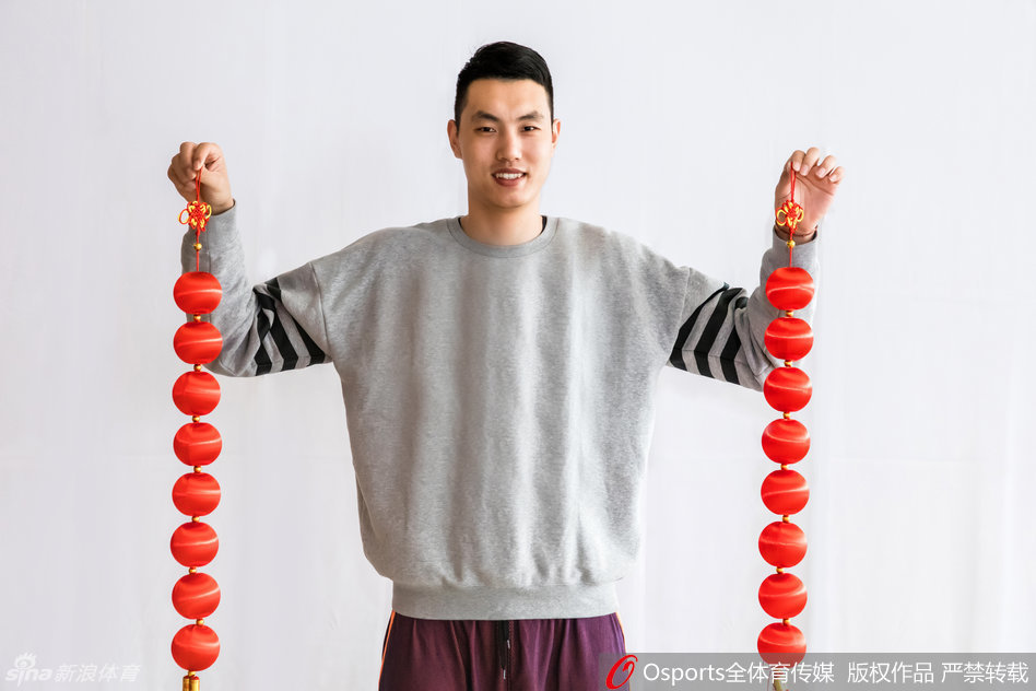 队友们围坐在一起，手里举着厚厚一摞红包，脸上绽放出孩子般的笑容，背景中隐约可见的冠军旗似乎也在为这喜庆时刻增添荣耀的光芒。